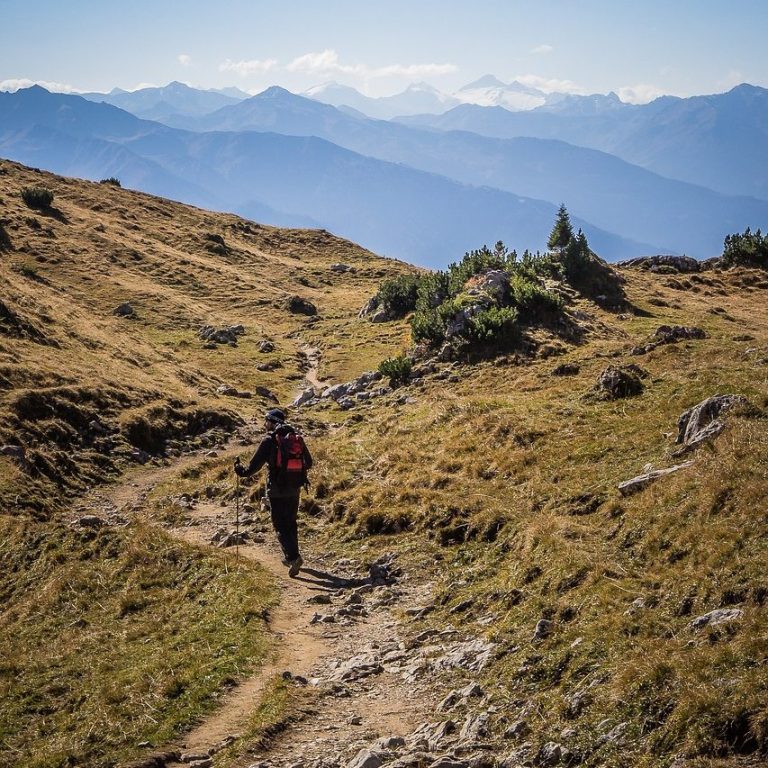 Eine Person wandert auf einem Pfad durch eine bergige Landschaft.