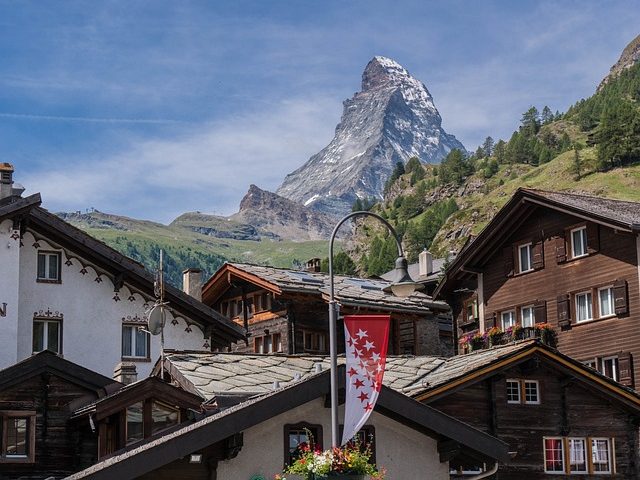 Bergpanorama mit dem Matterhorn und typischen alpinen Chalets im Vordergrund.