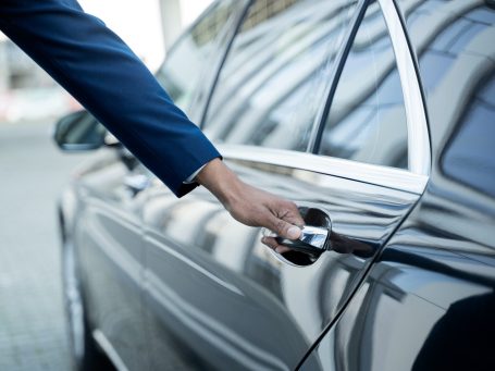 Eine Hand öffnet die Tür eines eleganten Autos.