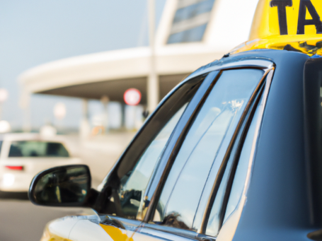 Taxis warten vor einem Flughafen mit modernem Gebäude im Hintergrund.