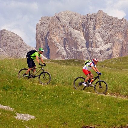 Zwei Radfahrer auf einem schmalen Pfad in bergiger Landschaft.